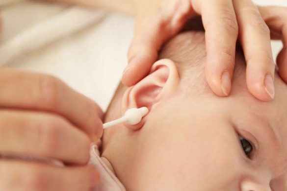 Gros plan sur un adulte qui utilise un bâtonnet ouaté à embout sécurisé pour nettoyer les oreilles d'un bébé.
