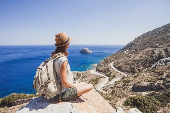 Une femme voyageur responsable avec un sac à dos contemple un paysage côtier sauvage.