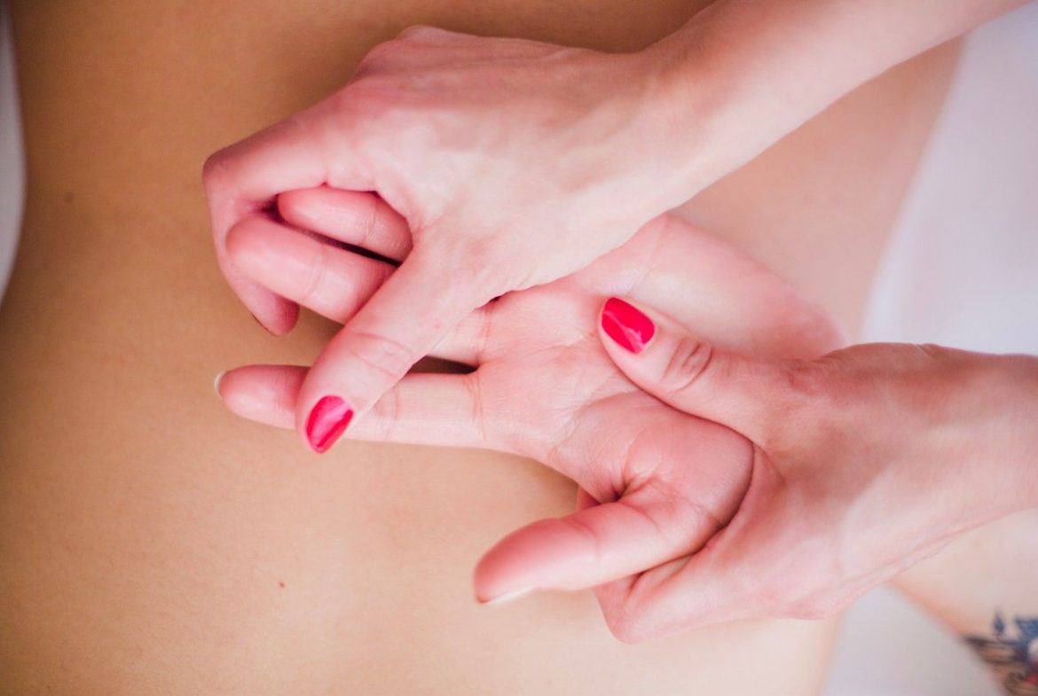Praticienne effectuant une pression ciblée sur la main lors d'un massage des méridiens en médecine chinoise.